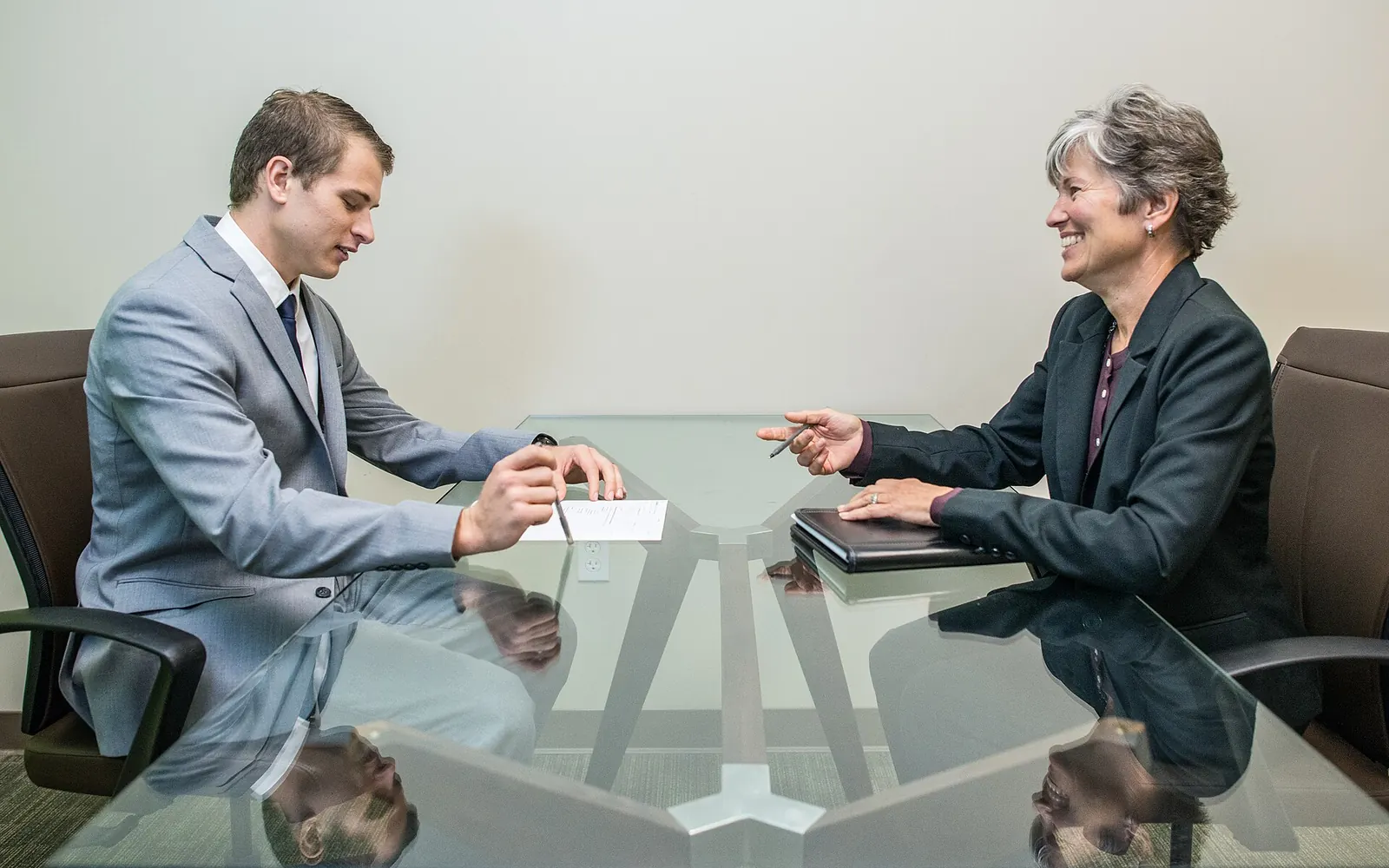 A young professional in a suit gesturing while speaking across a conference table