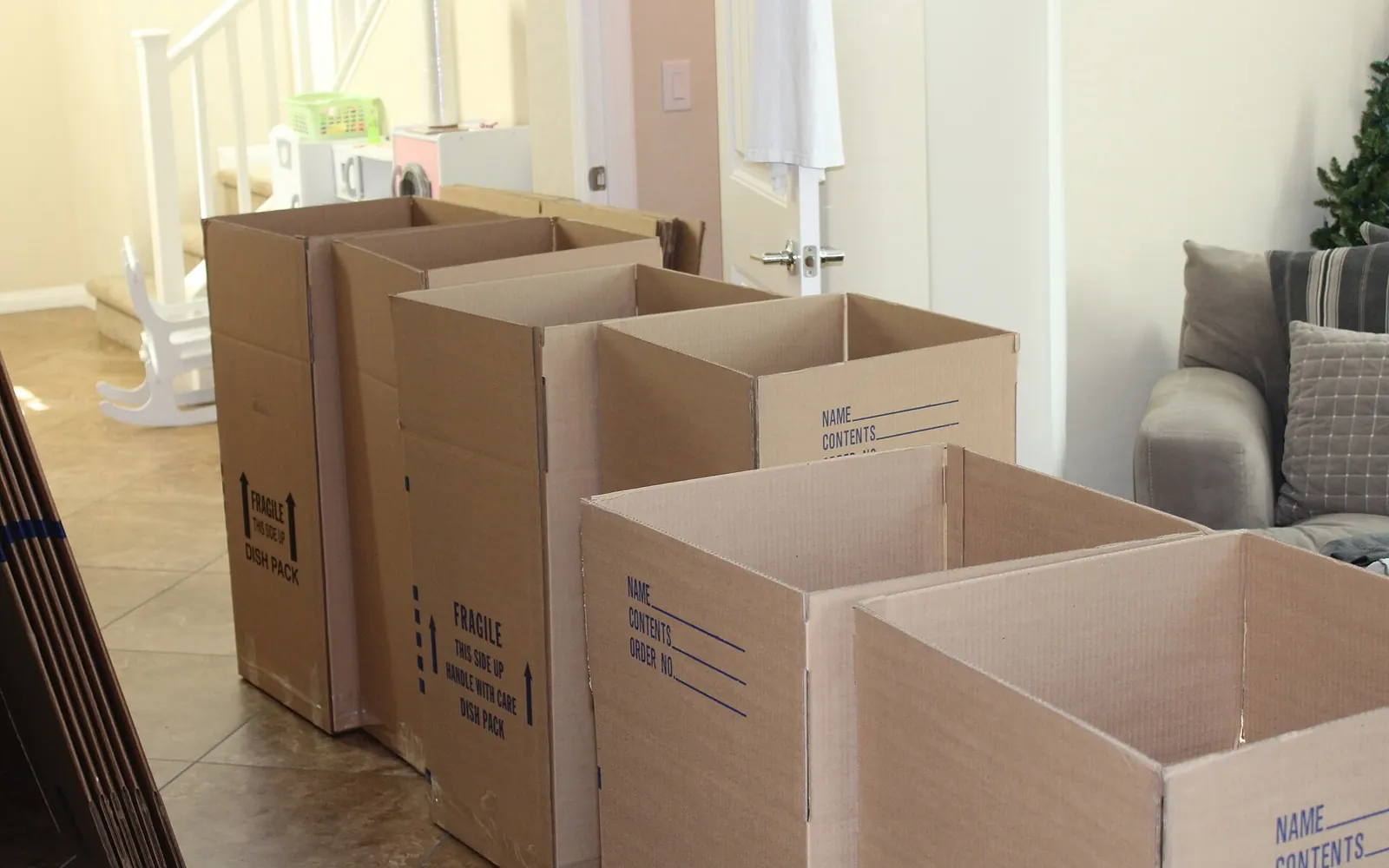 Stack of cardboard moving boxes labeled Fragile and Dish Pack inside a home